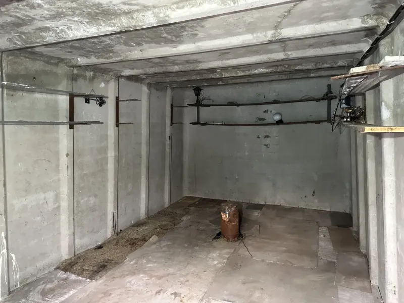 Leerer Betonraum mit Rohren und Beleuchtung, Garageninnenraum.