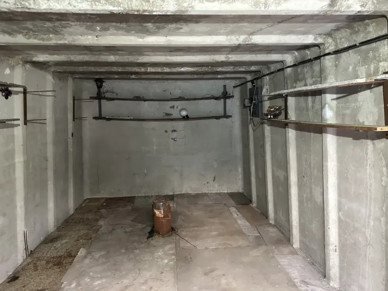 Leerer Betoninnenraum von Garagen mit Regalen und Beleuchtung.