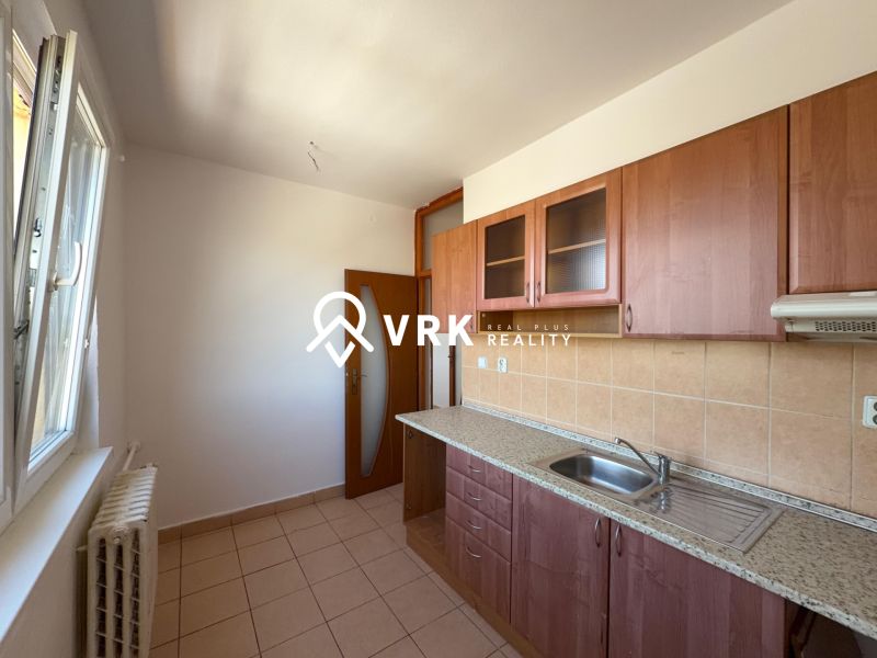 Küche in einer 2-Zimmer-Wohnung mit Keramikfliesen und Holzschränken.