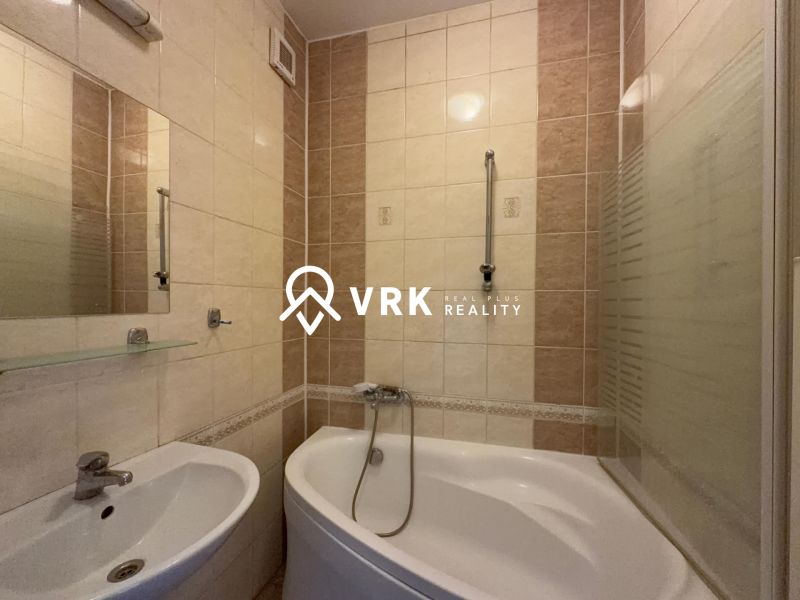 Badezimmer in einer 2-Zimmer-Wohnung mit Badewanne und Waschbecken, helle Fliesen.