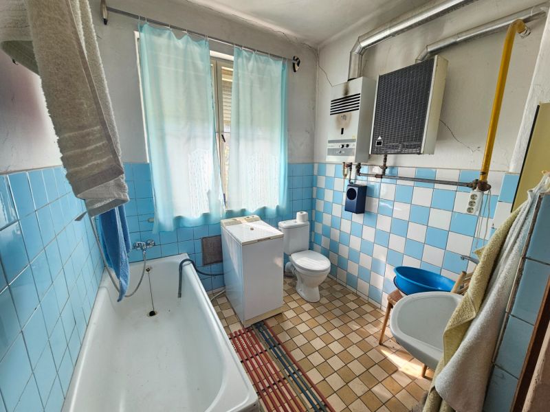 Ein Badezimmer in einem Einfamilienhaus mit blauen Fliesen, einer Badewanne und einem Waschbecken.
