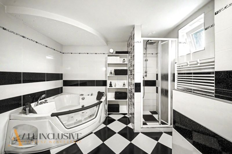 Ein Badezimmer in einem Einfamilienhaus mit Whirlpool, Dusche und schwarz-weißen Fliesen.