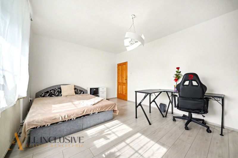 Ein Zimmer eines Einfamilienhauses mit einem Bett, einem Tisch und einem Stuhl auf einem Boden mit Holzdekor.