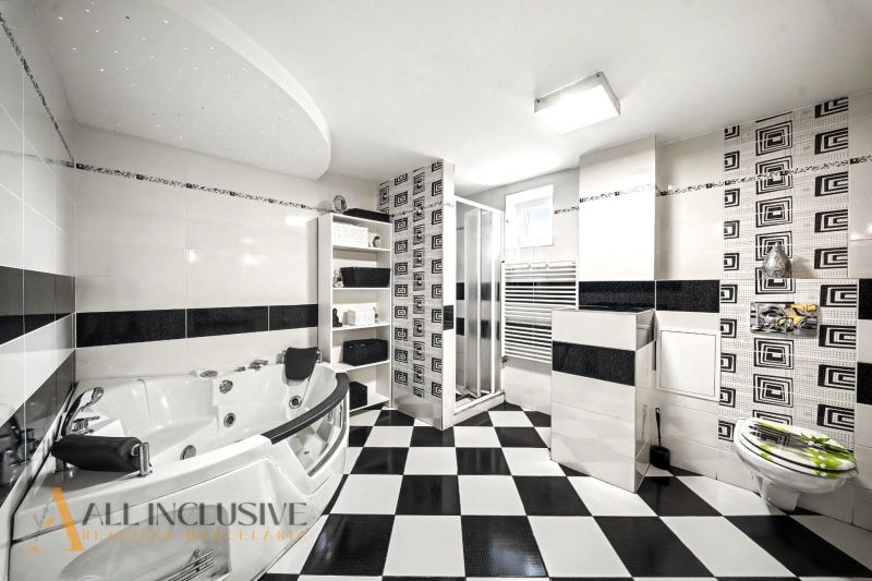 Schwarz-weißes Badezimmer mit Badewanne und Dusche in einem Einfamilienhaus.