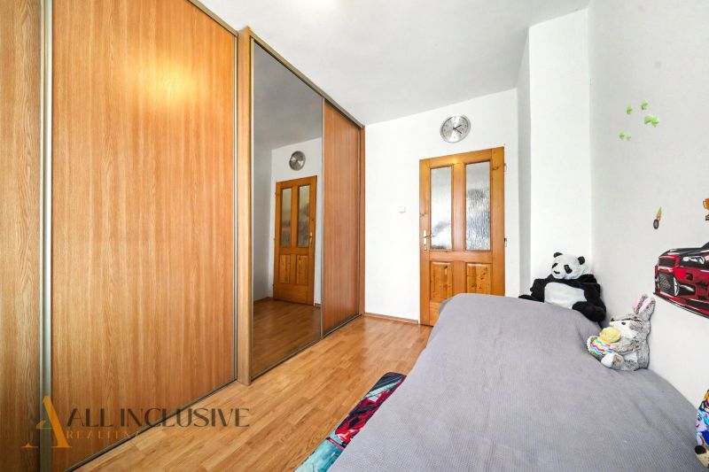 Ein Schlafzimmer in einem Einfamilienhaus mit einem Holzboden und einem großen Schrank mit Spiegel.