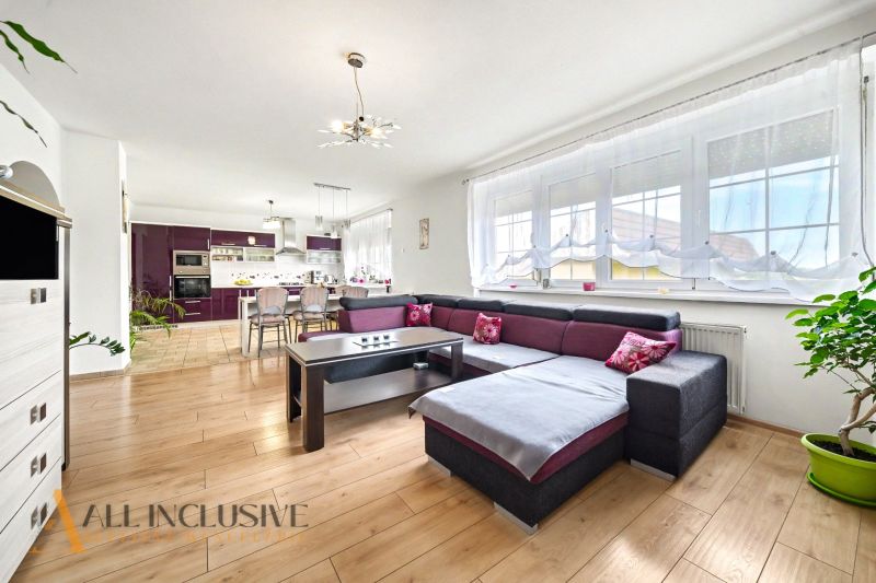 Wohnzimmer in einem Einfamilienhaus mit geräumigem Sofa und Boden in Holzoptik.