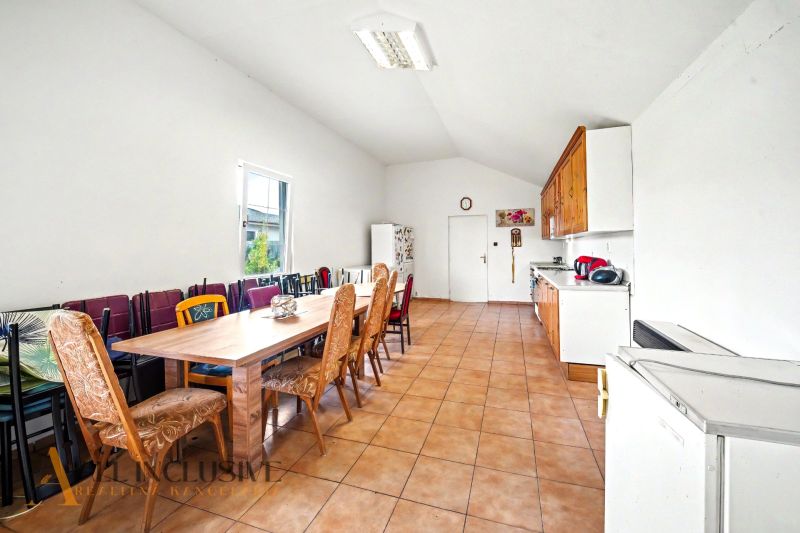 Eine geräumige Küche in einem Einfamilienhaus mit einer langen Essgruppe und Fliesenboden.