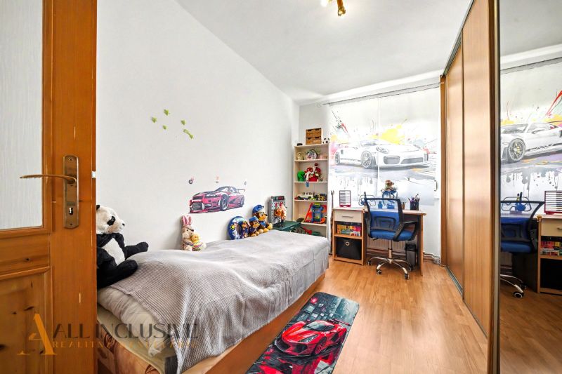 Kinderzimmer in einem Einfamilienhaus mit Spielzeug, Bett und Boden in Holzoptik.