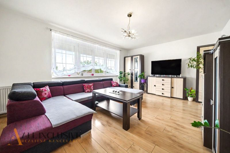 Wohnzimmer in einem Einfamilienhaus mit Ecksofa und Boden in Holzoptik.