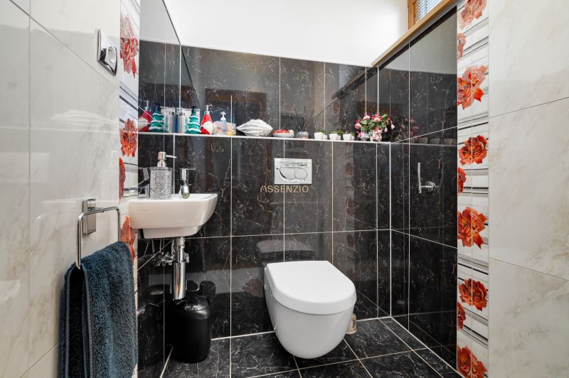 Ein Badezimmer in einem Einfamilienhaus mit dunklen Fliesen und bunten Blumenmotiven.