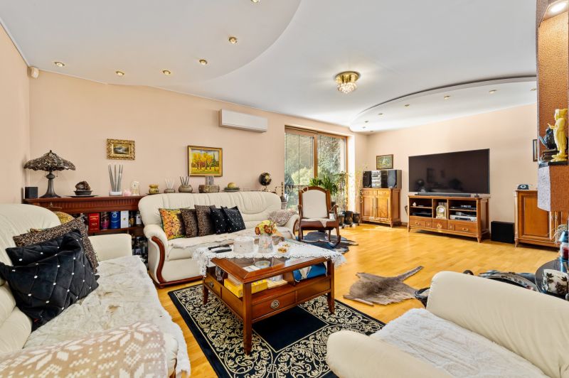 Helles Wohnzimmer in einem Einfamilienhaus mit bequemen Sitzgelegenheiten und einem Boden in Holzoptik.