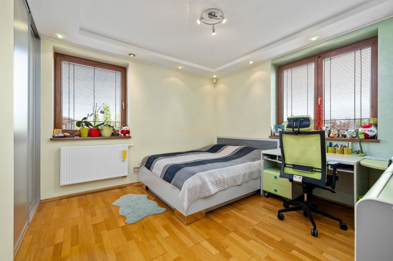 Kinderzimmer in einem Einfamilienhaus mit Bett, Schreibtisch und Boden in Holzoptik.