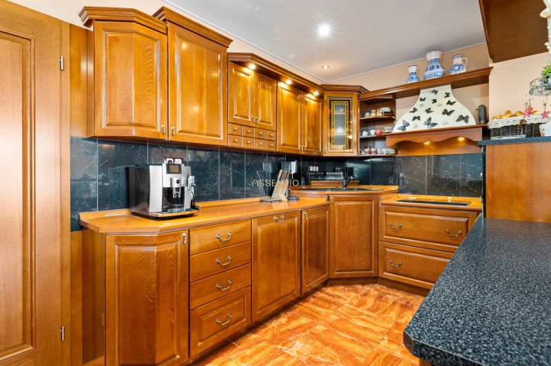 Küche in einem Einfamilienhaus mit Holzschränken und einem Boden in Holzoptik.