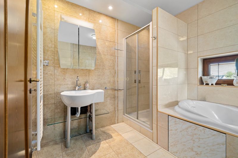Badezimmer mit Badewanne, Dusche und Waschbecken in einem Einfamilienhaus.