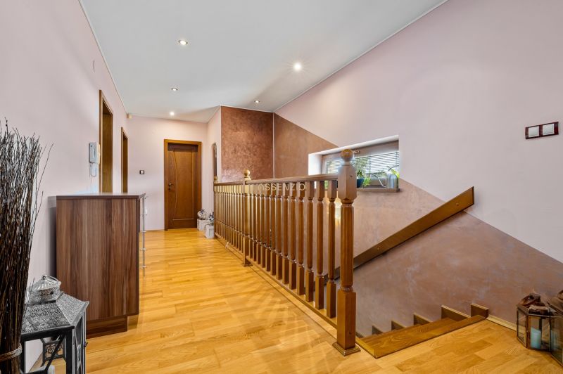 Flur mit Treppe in einem Einfamilienhaus, Boden mit Holzdekor, Spiegel und Pflanzen.