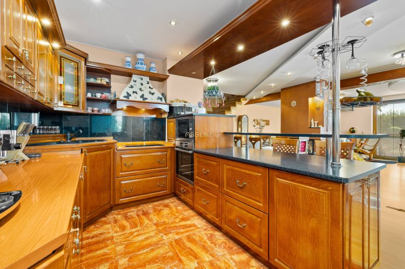 Eine Küche in einem Einfamilienhaus mit Holzschränken und einem Boden in Holzoptik.