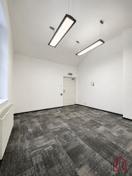 Büros mit Teppichboden und hängenden Leuchten in neutralen Farben.