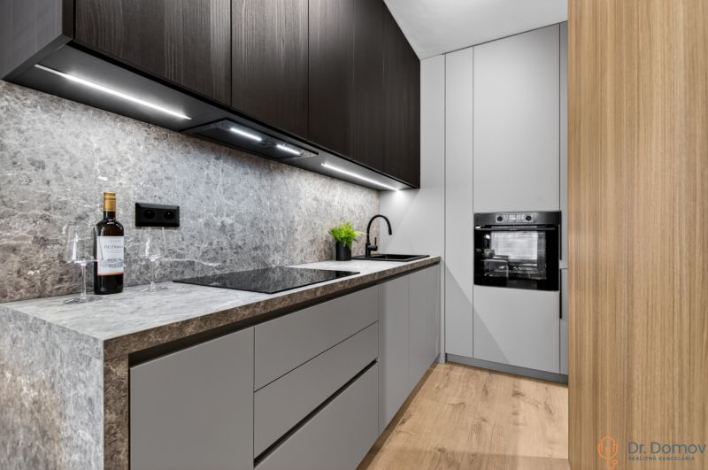 Küche in einer 2-Zimmer-Wohnung mit Holzboden und stilvollen Schränken.