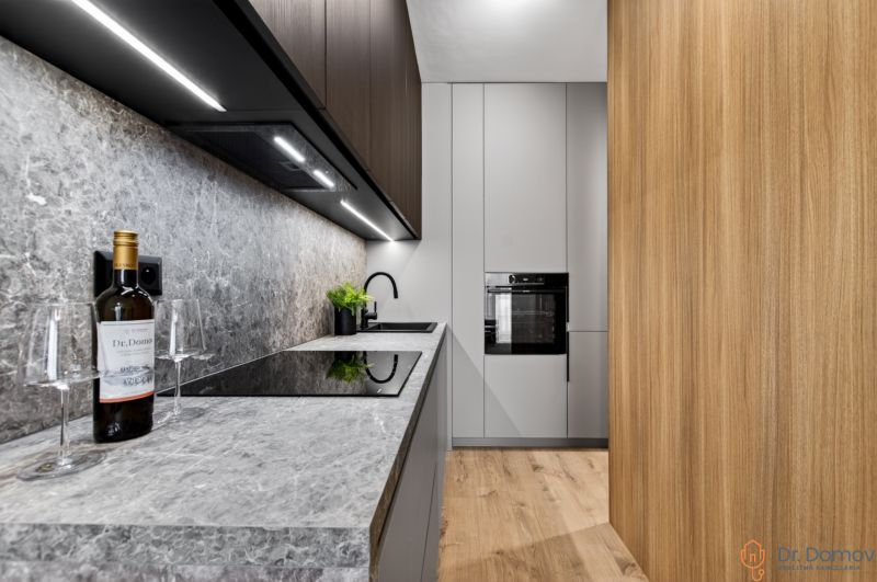 Küche in einer 2-Zimmer-Wohnung mit grauer Arbeitsplatte und Boden in Holzoptik.