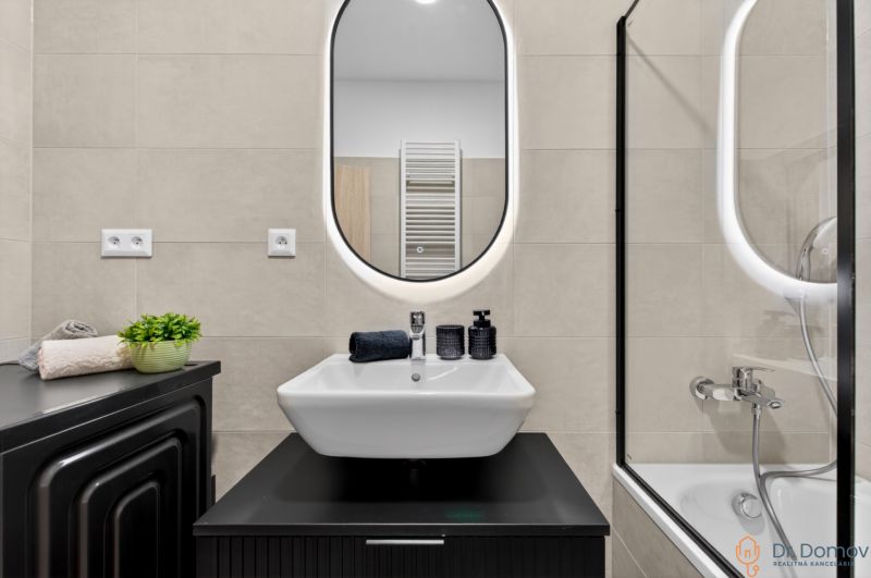 Badezimmer in einer 2-Zimmer-Wohnung mit Waschbecken, Spiegel und Badewanne. Accessoires in schwarzer Farbe.