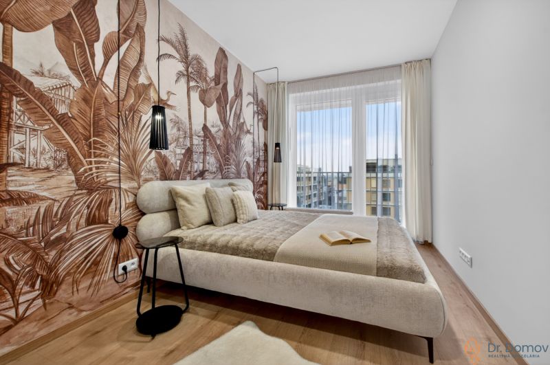 Schlafzimmer in einer 2-Zimmer-Wohnung mit tropischer Tapete und Holzboden.
