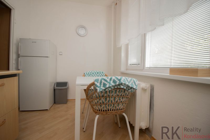 Küche in einer Einzimmerwohnung mit Holzboden, Tisch und Stühlen.