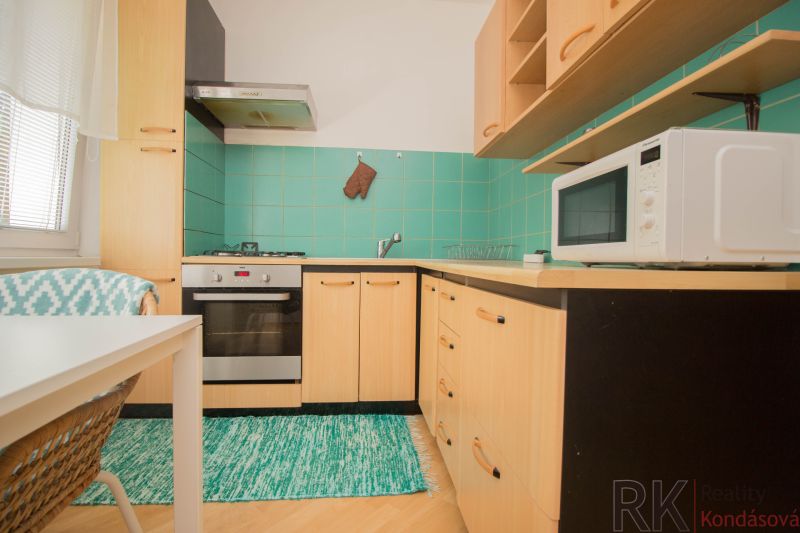 Küche in einer Einzimmerwohnung mit Gasherd und Mikrowelle, Boden mit Holzdekor.