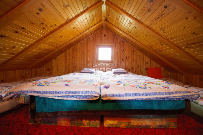 Eine Hütte mit Holzverkleidung hat ein Doppelbett unter einer Holzdecke.