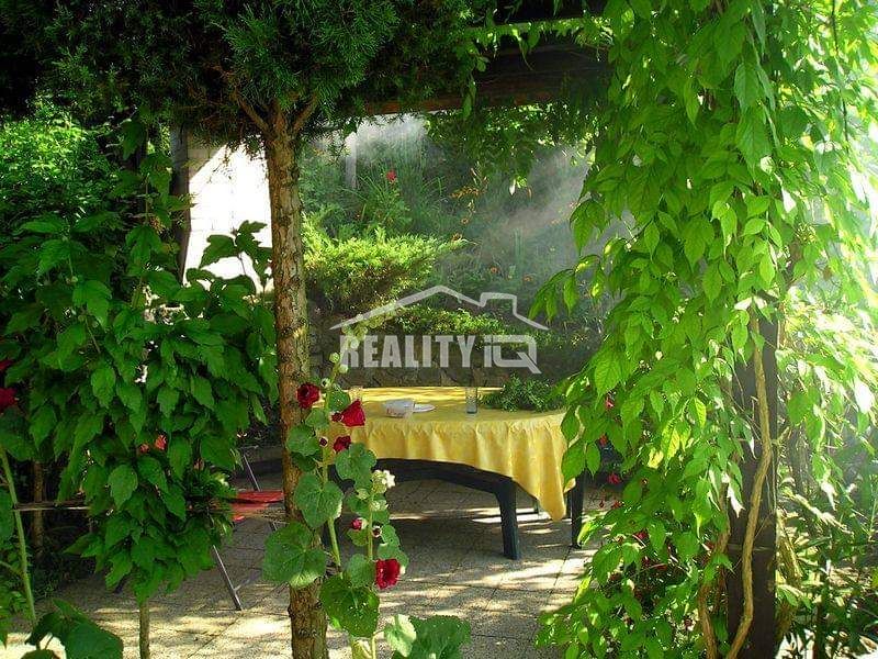 Gartenmöbel bei der Hütte in Žilina, umgeben von Grün und Blumen.