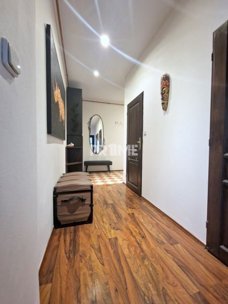 Der Flur einer 3-Zimmer-Wohnung mit einem Boden in Holzoptik und Wanddekorationen.