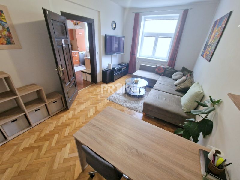 Das Wohnzimmer in der 3-Zimmer-Wohnung verfügt über eine bequeme Sitzgarnitur und einen Boden mit Holzdekor.