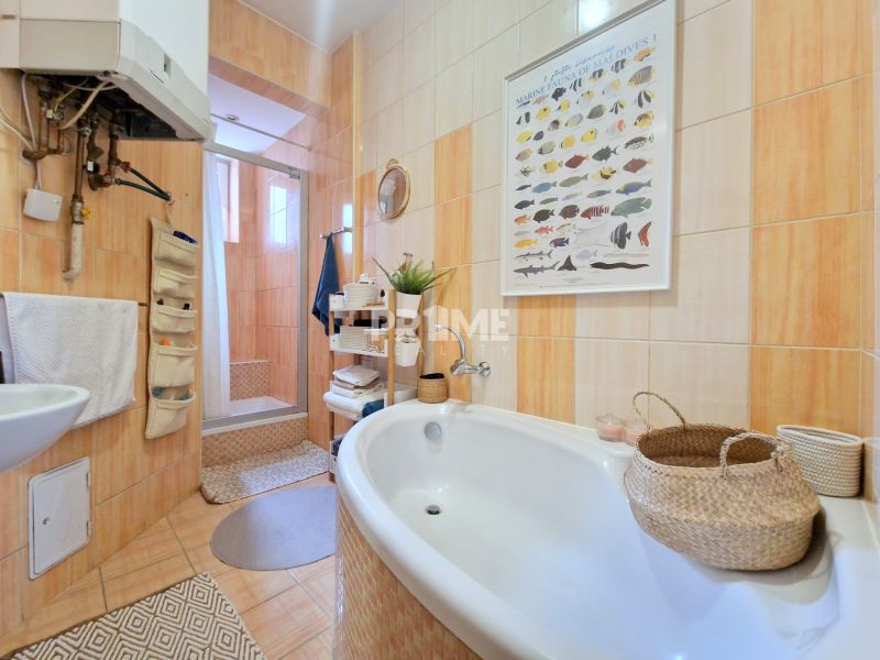 Badezimmer in einer 3-Zimmer-Wohnung mit Badewanne, Dusche und Körben für Zubehör.