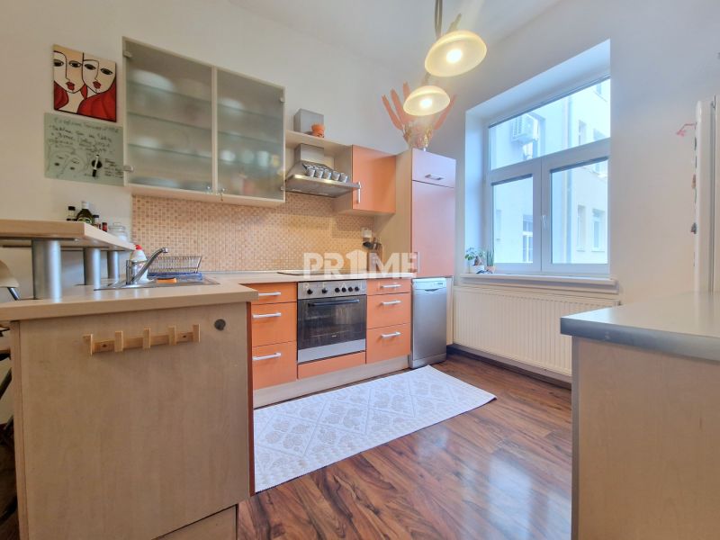 Küche mit orangefarbenen Schränken, Holzboden, in einer 3-Zimmer-Wohnung.