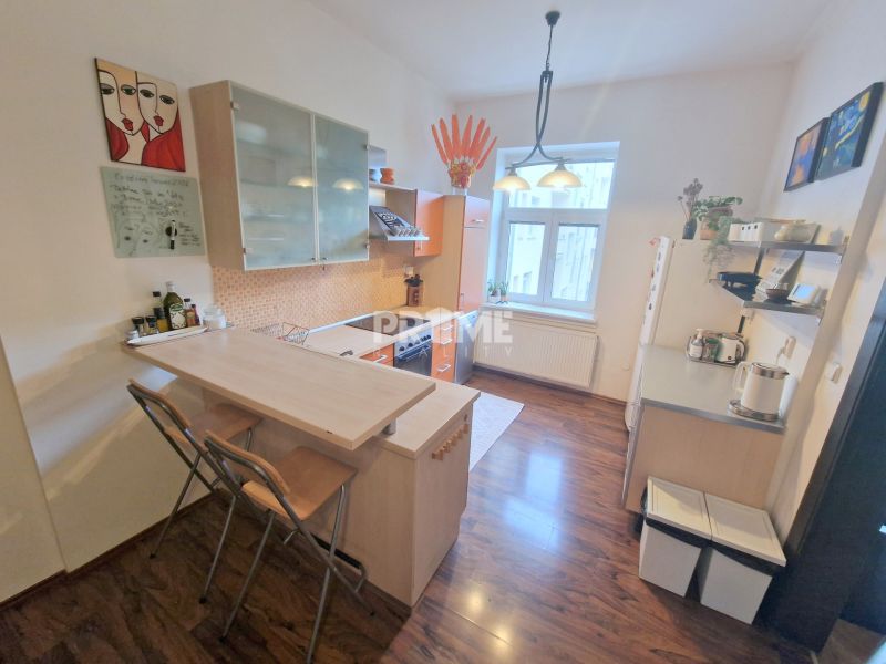 Küche in einer 3-Zimmer-Wohnung mit Bartresen, Regalen und Bodenbelag in Holzoptik.