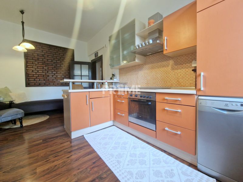 Küche in einer 3-Zimmer-Wohnung mit Holzboden und Ziegelwand.
