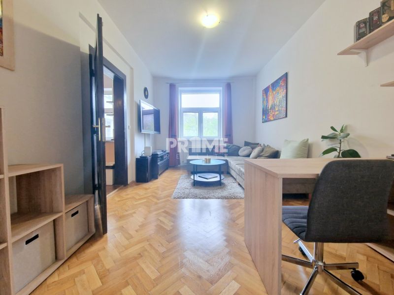 Wohnzimmer mit Holzboden, Sofa und Schreibtisch in einer 3-Zimmer-Wohnung.
