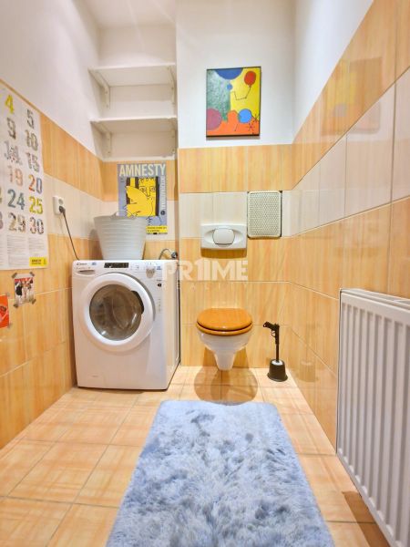 Badezimmer mit Waschmaschine, Toilette und Kunstbild in einer 3-Zimmer-Wohnung.