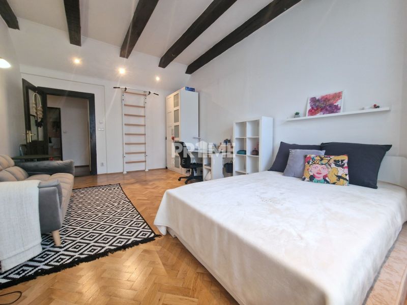 Ein Zimmer mit einem Bett, einem Sofa und einem Boden mit Holzdekor in einer 3-Zimmer-Wohnung.