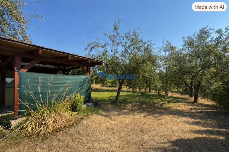 Eine Hütte im Weinberg in Lučenec, umgeben von Bäumen und Rasen.