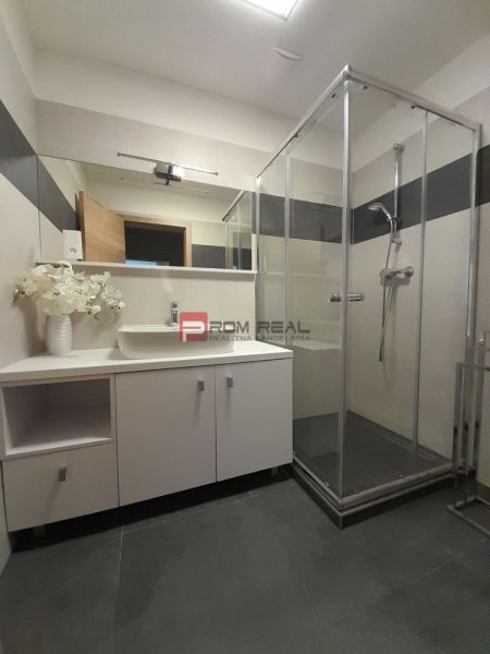 Badezimmer in einer 2-Zimmer-Wohnung mit verglaster Duschkabine und großem Spiegel.