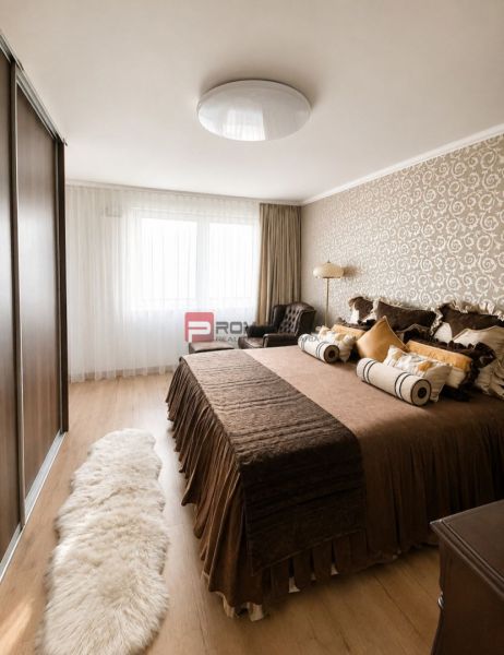Schlafzimmer in einer 2-Zimmer-Wohnung mit Holzboden, gemütlichem Bett und gemusterten Tapeten.