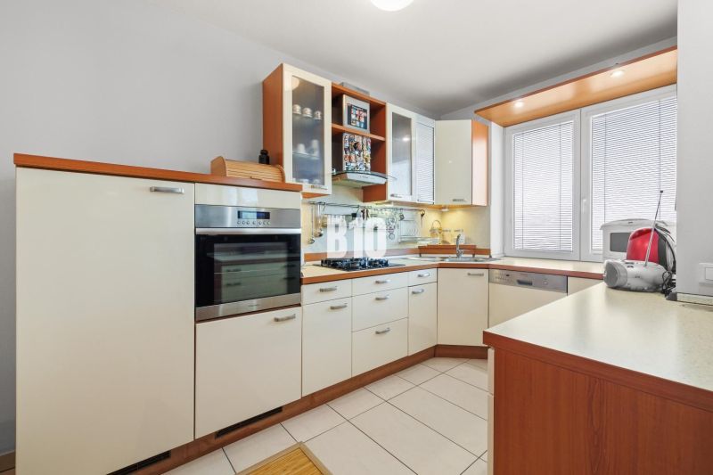 Küche in einer 4-Zimmer-Wohnung mit weißen Schränken und eingebauten Geräten.