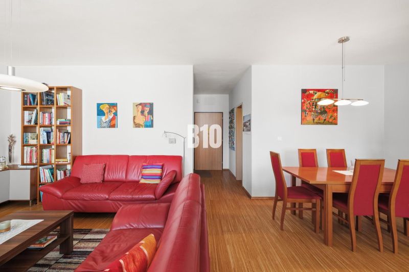Rote Ledersofas und ein Esstisch in einer 4-Zimmer-Wohnung mit Holzboden.