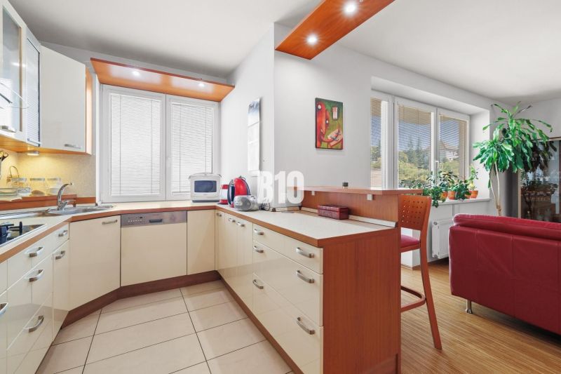 Küche in einer 4-Zimmer-Wohnung mit Eckküche, Bartresen und hellem Interieur.