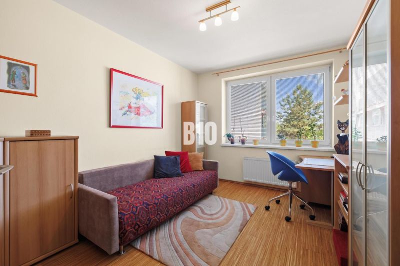 Zimmer in einer 4-Zimmer-Wohnung mit Holzboden, Sofa und Schreibtisch.