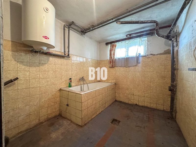 Badezimmer in einem Einfamilienhaus mit Fliesen und Badewanne, mit niedrigem Fenster und Gasheizung.