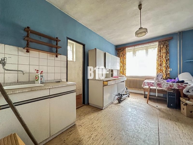 Küche in einem Einfamilienhaus mit Möbeln und Boden in Holzoptik.