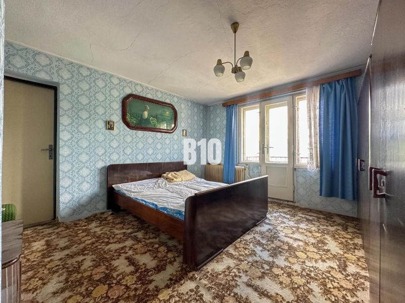 Schlafzimmer in einem Einfamilienhaus mit gemustertem Teppich und blauen Vorhängen.