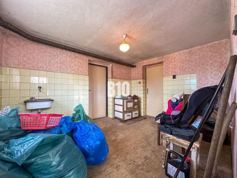 Innenraum eines Einfamilienhauses mit Waschbecken, Holzboden und gelagerten Gegenständen.