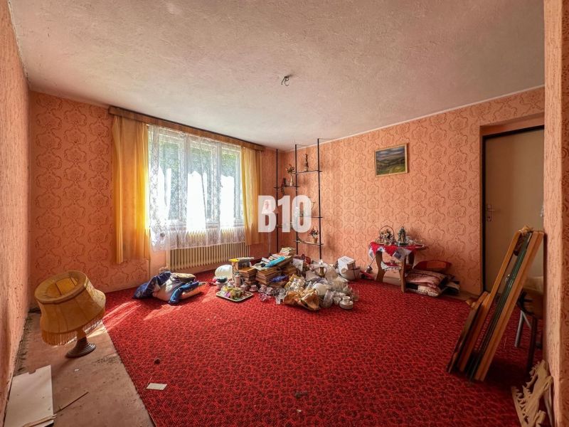 Ein Zimmer in einem Einfamilienhaus mit rotem Teppich und vielen Gegenständen überall.